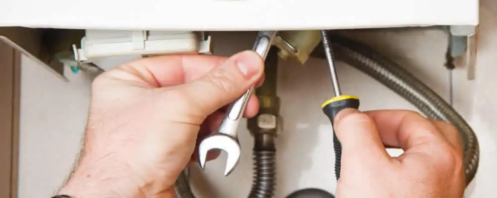 Boiler repair technician tightening pipe fittings and connections in Los Angeles, CA