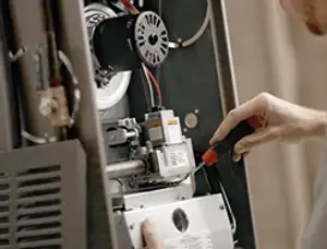 Furnace repair technician inspecting internal components and wiring in Los Angeles, CA