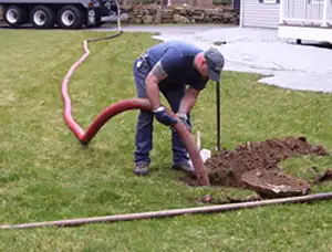 Septic pumping technician servicing a residential septic tank with a vacuum hose in Los Angeles, CA