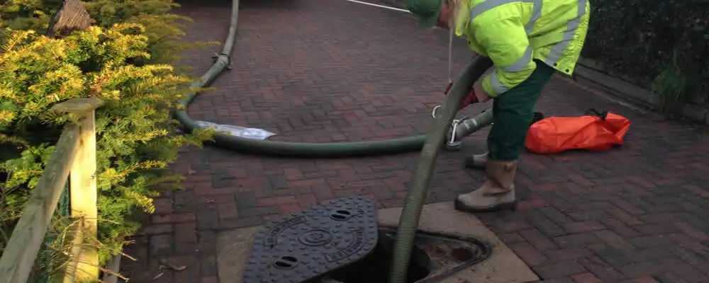 Septic tank cleaning technician servicing a septic tank with a vacuum hose in Los Angeles, CA