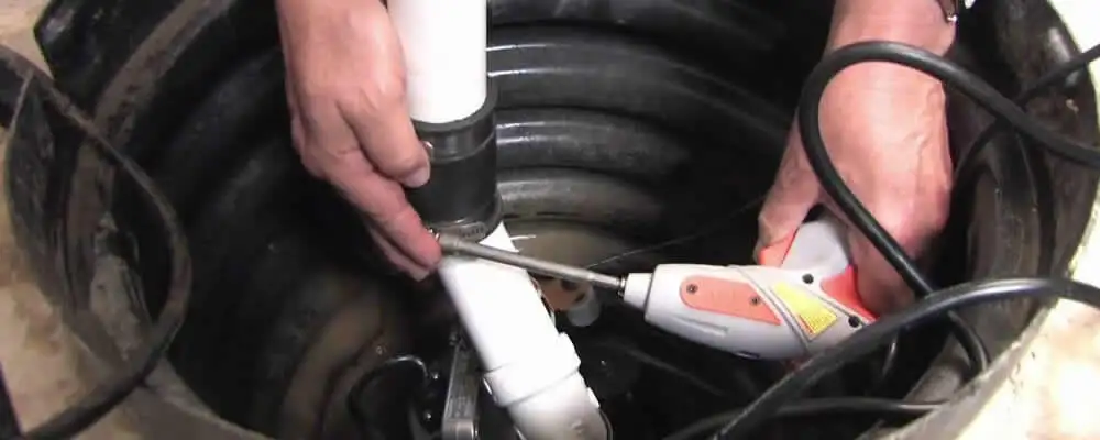 Sump pump installation technician connecting PVC discharge piping in Los Angeles, CA